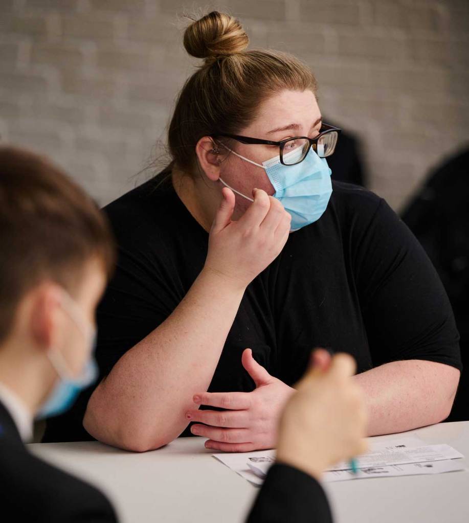 Youth worker wearing a mask speaking to school pupils