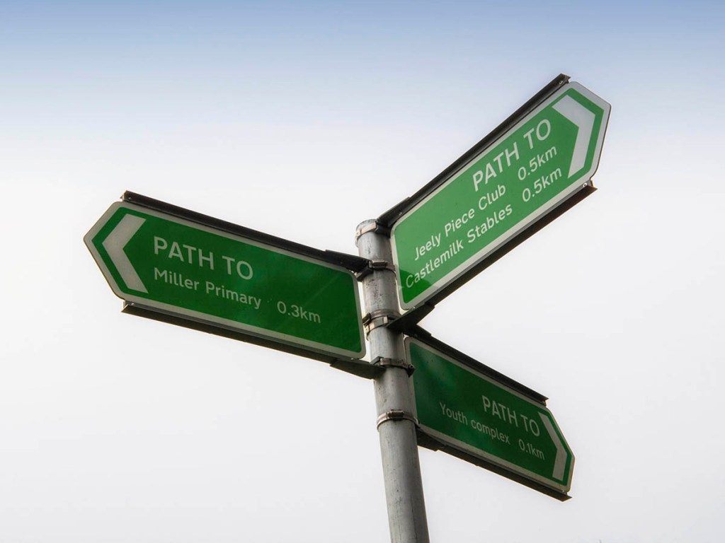 A green signpost pointing in three directions